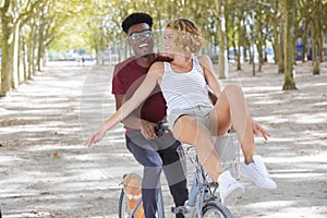 joyful couple riding one bike in public park photo