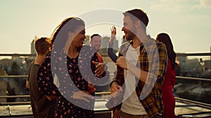 Joyful couple rocking at rooftop disco. Multiracial people dancing at party.