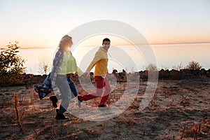 Joyful couple running through the riverside together