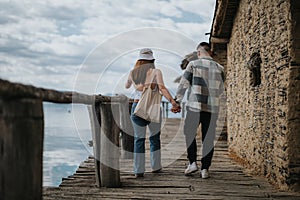 Joyful couple walking hand in hand on a rustic pier during a serene vacation