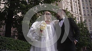 A joyful couple in wedding attire, donning formal wear with smiles and gestures.