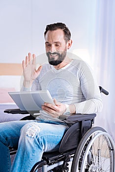 Joyful crippled man waving at the screen