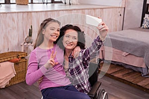 Joyful crippled woman and girl taking selfie