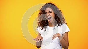 Joyful curly-haired woman dancing celebrating success, good mood, moving music