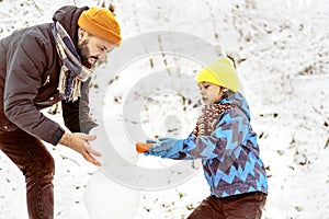 Joyful dad and son enjoying building a snowman.