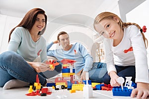 Joyful delighted family sitting around the meccano set