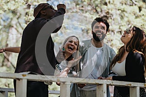 Joyful diverse friends laughing together in a sunny urban park, celebrating carefree moments of friendship