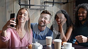 Joyful diverse mates company posing for group selfie at cafe