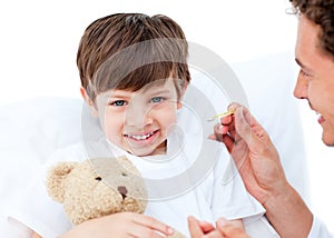 Joyful doctor taking little boy's temperature