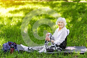 Joyful elderly lady training on green grass