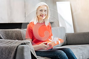 Joyful elderly woman holding a present