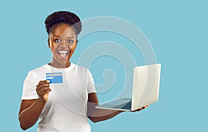 Joyful emotional woman with credit card and laptop enjoying using online banking.