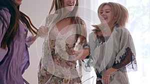Joyful emotions, happy young women jumps fun on bed during the pajama party in slow motion