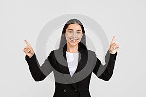 Joyful european businesswoman pointing upwards with both hands