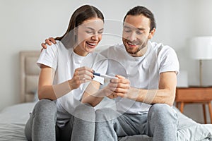 Joyful european couple with positive pregnancy test