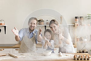 Joyful excited parents and little kid having fun at table