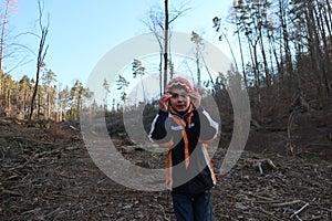 Joyful expression and sign language. The boy stands facing the camera, he signs. Autistic child on a forest pasture.