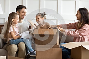 Joyful family couple having fun with children in new apartment.