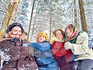 Joyful family ethnic dress with shawls and earflap hats in a winter forest in carnival Maslenitsa in Russia. Tourists in