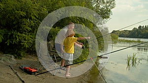 Joyful family of fishermen with spin fishing rod catching fish on river