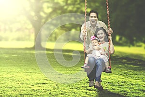 Joyful family playing on swing