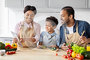 Joyful family preparing a meal with a tablet
