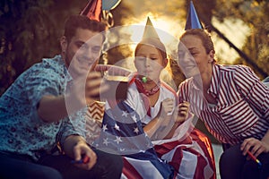 Joyful family of three with party hats and blowers, celebrating birthday of girl together, dad taking a picture of them