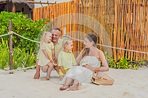 A joyful family, two girls, dad, and a pregnant mom, bask in tropical beach bliss, celebrating a radiant pregnancy