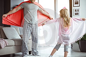 Joyful father and daughter playing in mantles at home