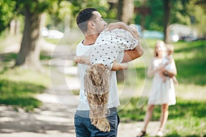 Joyful father and lovely daughter outdoor activity. Happy father holds his adorable baby headfirst in summer park