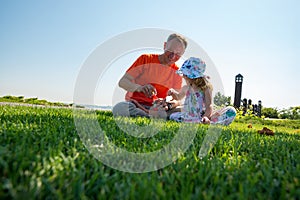 Joyful father with a small daughter are playing on a green meadow