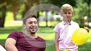 Joyful father and son blowing balloons for birthday party, fooling around, funny