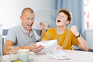 Joyful father and son cheering after reading letter from college