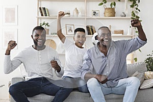 Joyful Father, Son And Grandfather Watching Soccer On TV And Cheering