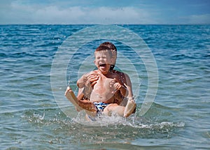 Joyful father and son having fun in water on beach in Croatia.Summer vacation