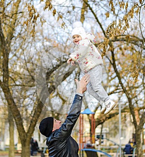 Joyful father tosses his daughter up. Walk the family in the park in the fall.