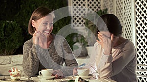 Joyful female friends discussing gossips, sitting cafe table laughing, leisure