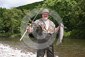 Joyful fisherman holding pink salmon.