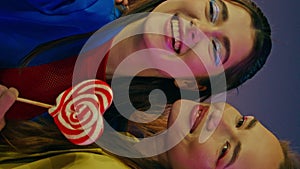 Joyful friends making selfie at night luna park vertically closeup. Happy girls