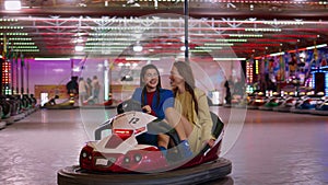 Joyful friends riding bumper car in luna amusement park. Smiling girls resting