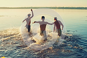 Joyful friends run into the water in a cloud of spray