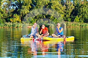 Joyful friends, a SUP surfers relax, eat apples and having fun