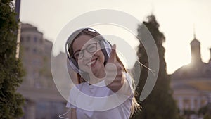 Joyful girl in big headphones shows thumb up 4K