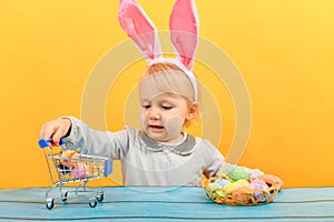 A joyful girl with bunny ears holds painted Easter eggs in a sho