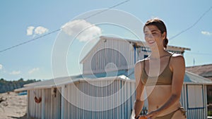 Joyful girl enjoying tennis game on sunny beach. Active young woman relaxing