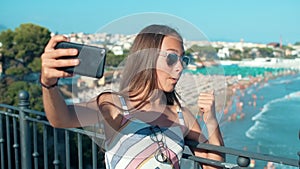 Joyful girl having video call outdoor. Teenager enjoying summer day at coastline