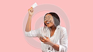 Joyful Girl Holding Smartphone And Credit Card Over Pink Background