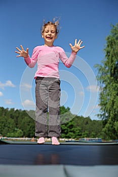 Joyful girl jumps on trampoline