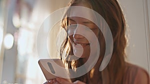 Joyful girl reading message sms in sunlight closeup. Happy teenager using mobile