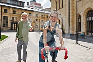 Joyful girl ride bicycle before blurred boyfriend